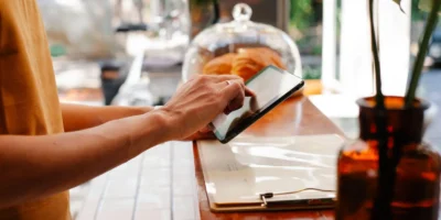 Restaurant staff member using a tablet at the counter to manage operations