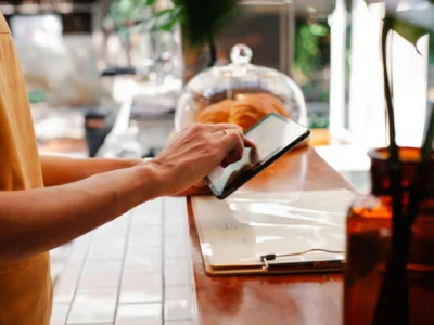 Restaurant staff member using a tablet at the counter to manage operations