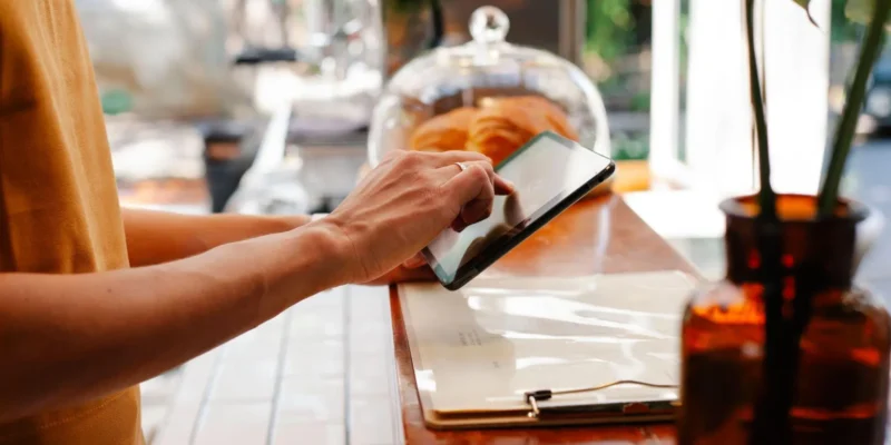 Why Every Restaurant Group Needs Data-Driven Operational Tools Restaurant staff member using a tablet at the counter to manage operations